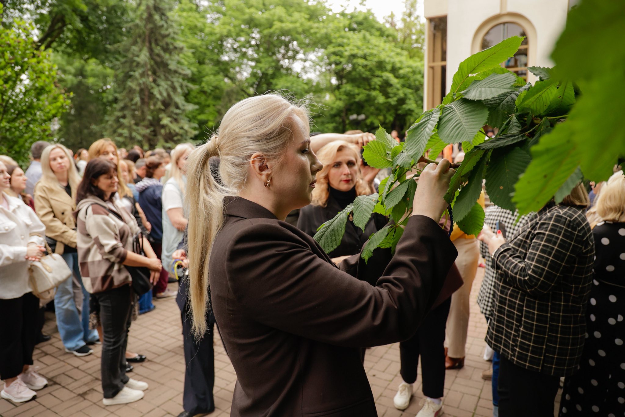 Учасниця акції пам'яті прив'язує дзвіночок до дерева